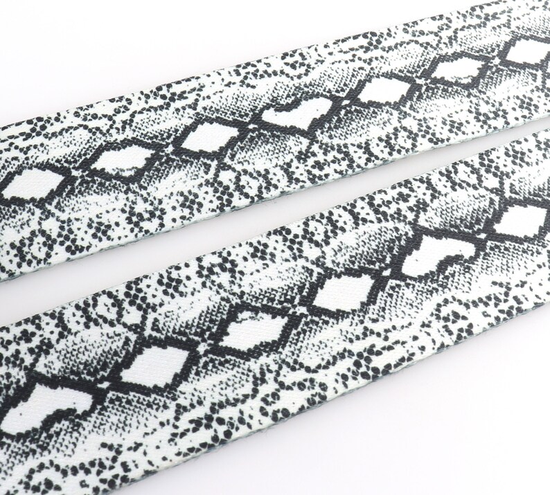 May include: White fabric with a black snake skin pattern.