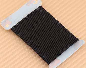 May include: A spool of black elastic string wound around a cardboard card with a cartoon design of clouds and stars.