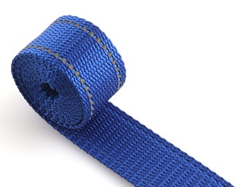 May include: A close-up of a blue webbing strap with a reflective gray stripe running along the edge. The strap is rolled up and ready to be used for a variety of purposes.