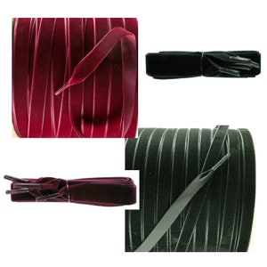 May include: Two spools of velvet ribbon, one burgundy and one black. The ribbon is flat and has a subtle sheen. The ribbon is wound around the spools and the ends are tied together.