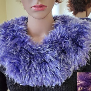 May include: A purple and white faux fur collar. The collar is soft and fluffy and would be a great addition to any winter outfit.