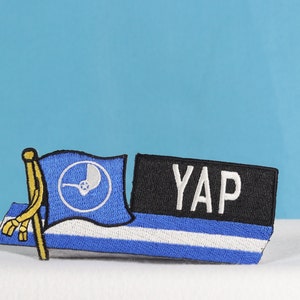 May include: A blue and white embroidered patch with a stylized symbol and the text "YAP" on a black background.