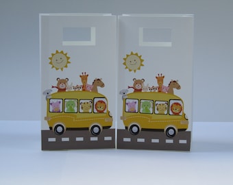May include: Two white gift bags with a yellow school bus carrying a variety of animals. The bus has a smiling sun above it. The bags have a cut-out handle.