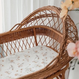 Peut inclure: Un berceau en osier avec un drap à motif floral blanc. Le berceau est fait d'osier tissé naturel et a une forme arrondie. Le drap est doux et confortable, et le berceau est parfait pour un bébé.