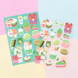 May include: Two sheets of stickers featuring cute cartoon characters enjoying matcha themed treats. The stickers include a bear, a cat, and a variety of desserts like matcha ice cream, cake, and mochi.