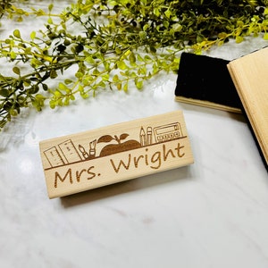 May include: A wooden desk nameplate with the text "Mrs. Wright" and a design of a pencil, ruler, apple, and calculator.