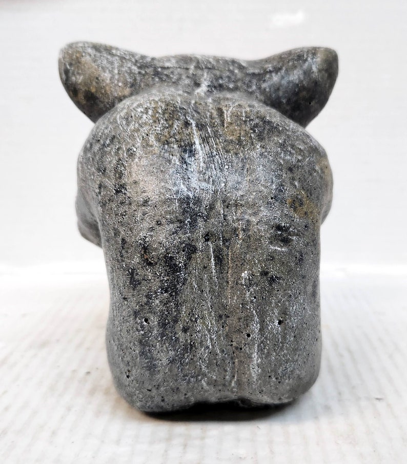 May include: A gray stone sculpture of a wolf's head. The sculpture is detailed and realistic, with a textured surface.