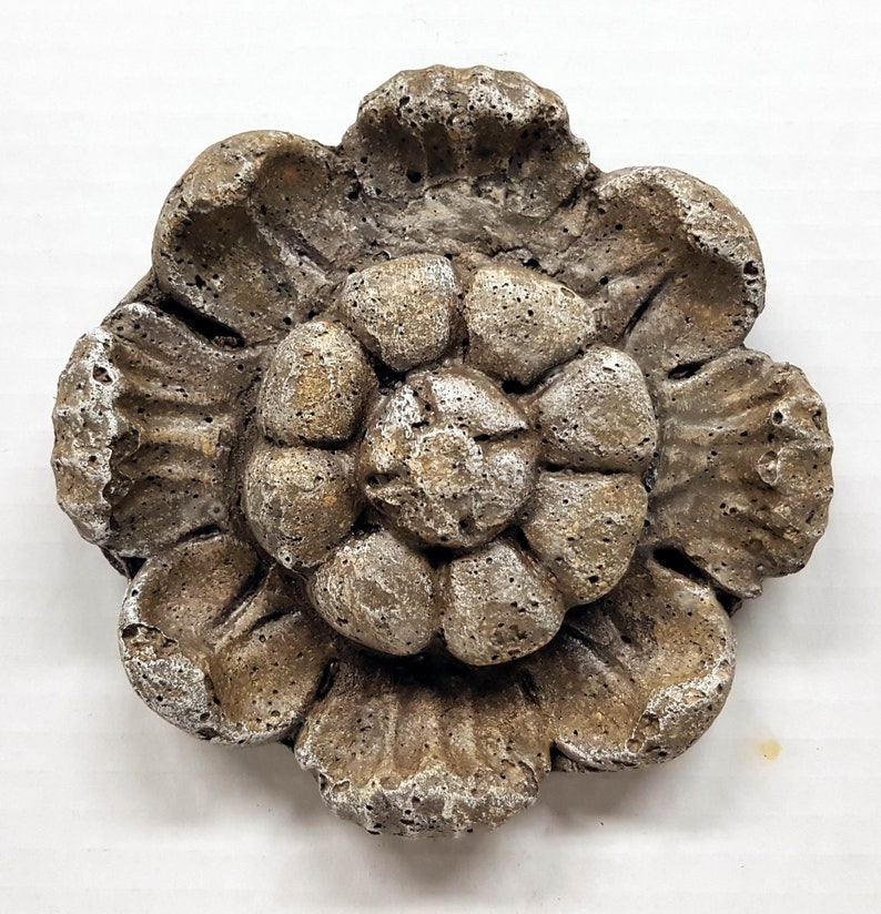 May include: A weathered, stone-like decorative flower with multiple layers of petals. The flower has a textured surface with shades of gray, brown, and white. The design is reminiscent of a classic floral motif, suitable for home decor.