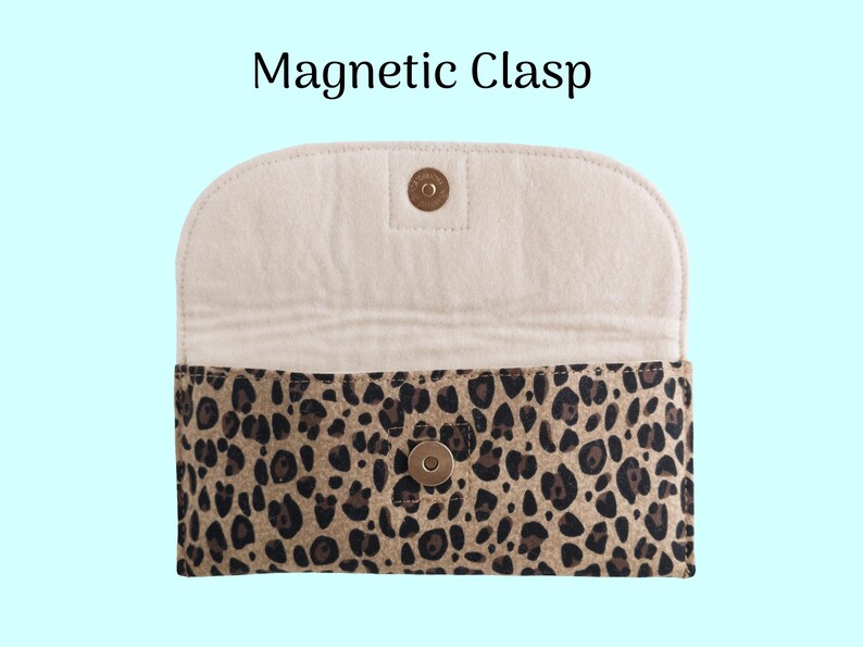 Puede incluir: Un bolso de mano con estampado de leopardo en el exterior y un interior color crema. El bolso tiene un cierre magn&eacute;tico. El texto "Magnetic Clasp" se muestra en la parte superior de la imagen. El bolso est&aacute; abierto, revelando el interior.