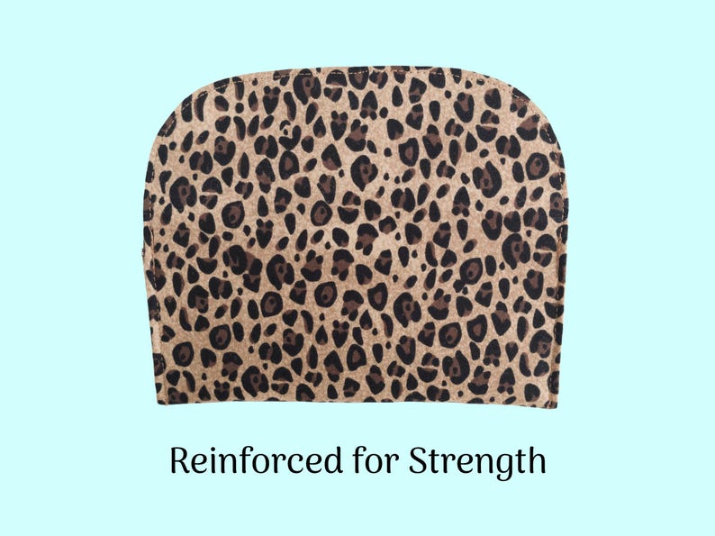 Puede incluir: Una tela con estampado de leopardo con manchas marrones y negras sobre un fondo beige. La tela est&aacute; curvada en la parte superior y tiene el texto "Reinforced for Strength" en la parte inferior. El fondo es azul claro.