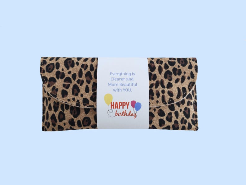 Puede incluir: Un bolso de mano con estampado de leopardo con una banda blanca con el texto "Everything is Clearer and More Beautiful with YOU." Debajo, "Happy Birthday" con gr&aacute;ficos de globos. El bolso es rectangular con solapa.