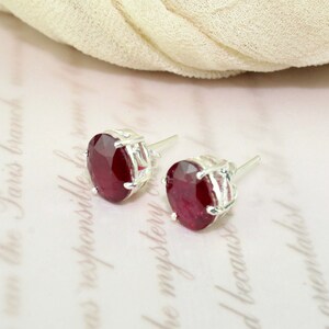 Puede incluir: Un par de pendientes de plata con piedras ovaladas rojas.
