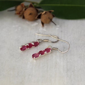Peut inclure: Boucles d'oreilles pendantes en argent avec trois pierres précieuses rubis de forme ovale.