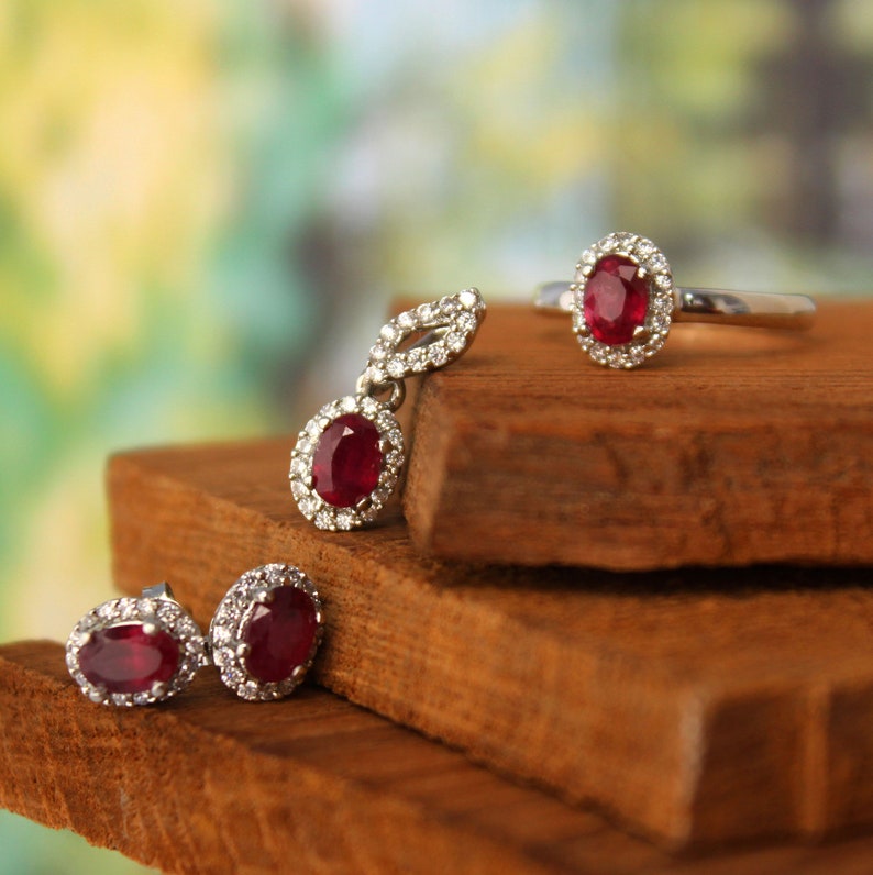 K&ouml;nnte beinhalten: Ein Schmuckset aus Rubin und Diamant mit einem Ring, Ohrringen und einem Anh&auml;nger. Die Rubine sind tiefrot und von kleineren Diamanten umgeben.