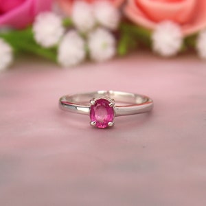 Puede incluir: Un anillo de plata con una piedra preciosa ovalada rosa engastada en un sencillo engaste de garras.