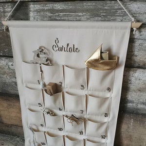 Personalized canvas advent calendar which can be used again every year. Featuring 24 pockets to mark each day of December it can be filled with small gifts. Off white, sand, ecru colors. Custom handmade product with wooden numbers gift box for kids.