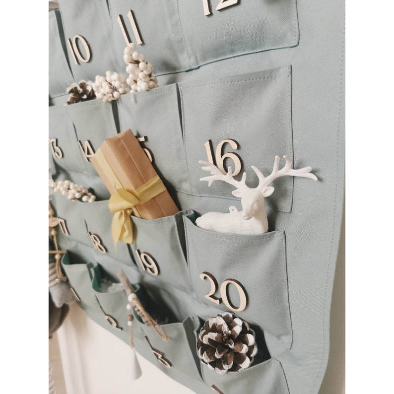 Countdown to Christmas with this canvas advent calendar, which can be used again  every year. Featuring 24 pockets to mark each day of December it can be filled with small gifts. Sage, old green colors. Handmade product. With wooden numbers. Gift box