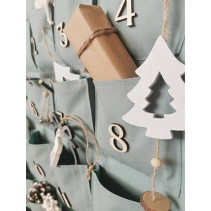 Canvas personalized advent calendar which can be used again every year. Featuring 24 pockets to mark each day of December it can be filled with small gifts. Sage, old green colors. Handmade product. With wooden numbers. Custom order gift box for kids