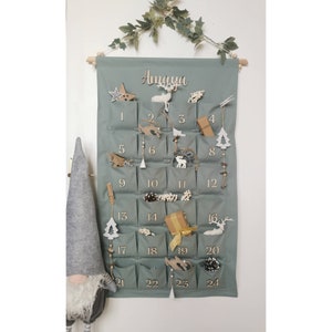 Canvas personalized advent calendar which can be used again every year. Featuring 24 pockets to mark each day of December it can be filled with small gifts. Sage, old green colors. Handmade product. With wooden numbers. Custom order gift box for kids