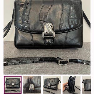 May include: Black leather crossbody bag with a textured, glossy finish. The bag features a silver-tone clasp with an ornate design and a long, adjustable strap. The bag's design includes vertical panels and crocodile-like accents.