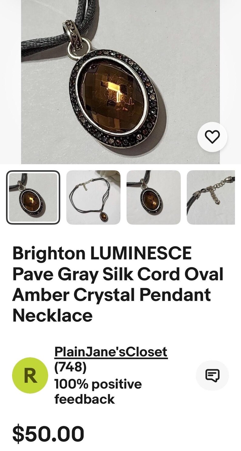 May include: An oval amber crystal pendant necklace with a gray silk cord. The pendant is surrounded by a silver-toned frame with small, dark-colored stones. The necklace is from Brighton.