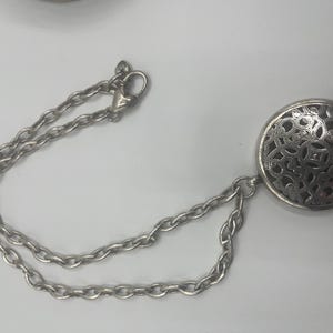 May include: A white ceramic mug with a black handle and the text "But First, Coffee" in a bold, black font. The mug is set against a blurred background, suggesting a cozy setting. The mug appears to be approximately 4 inches tall.