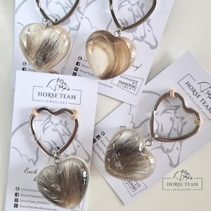 May include: Four silver heart-shaped keychains with clear resin hearts filled with horse hair. Each keychain has a small silver horse charm and the text "Horse Team Jewellery".