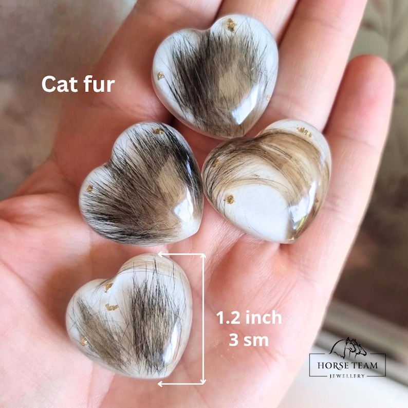 May include: Four heart-shaped resin keepsakes filled with cat fur and gold glitter. Each keepsake measures 3 cm in diameter.