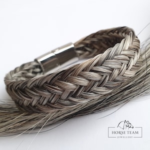 May include: A braided horsehair bracelet with a silver magnetic clasp. The bracelet is made with a mix of black and white horsehair.