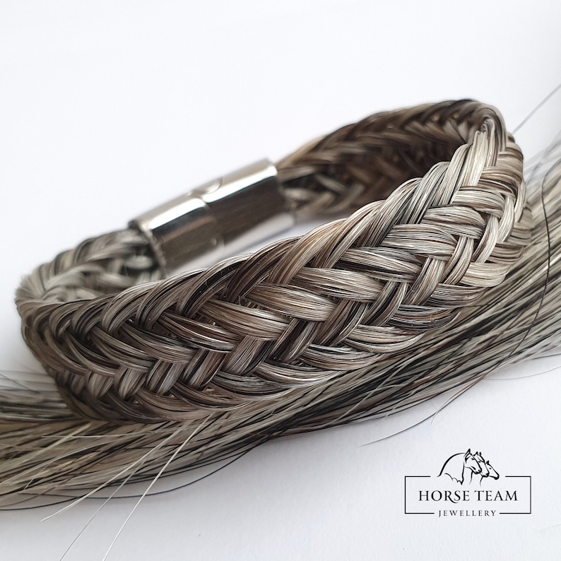 May include: A braided horsehair bracelet with a silver magnetic clasp. The bracelet is made with a mix of black and white horsehair.