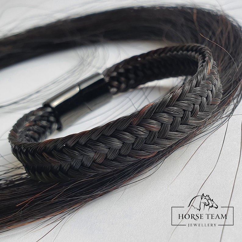 May include: A black braided horsehair bracelet with a black magnetic clasp. The bracelet is made with a woven pattern and is a unique piece of jewelry.