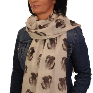 May include: A woman wearing a denim jacket and a white scarf with a repeating pattern of black and white border collie dog faces.