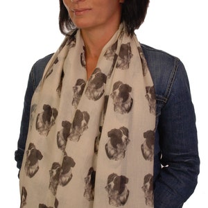May include: A beige scarf with a repeating pattern of black and white border collie dog faces.