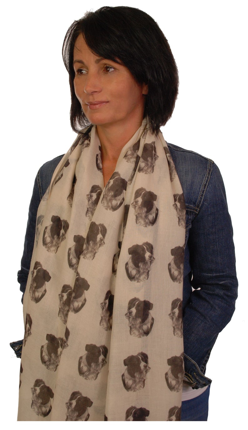 May include: A beige scarf with a repeating pattern of black and white border collie dog faces.