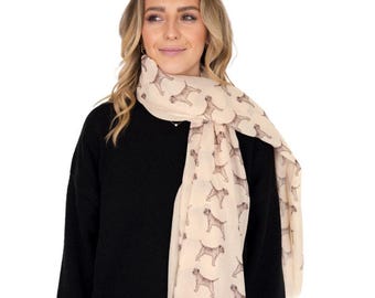 May include: A lightweight, cream-colored scarf featuring a repeating pattern of small, brown, illustrated dogs. The scarf is draped around the neck, showcasing the detailed canine print against the neutral fabric background in a simple, classic style.