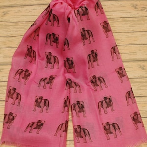 May include: A pink scarf with a repeating pattern of brown bulldog silhouettes.