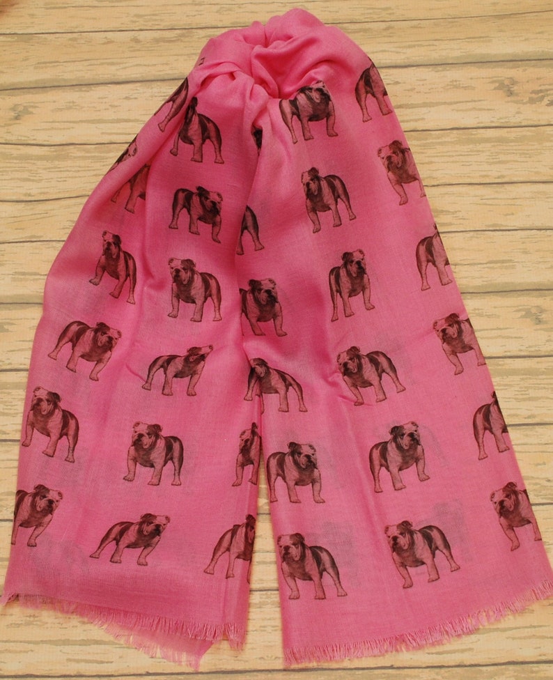 May include: A pink scarf with a repeating pattern of brown bulldog silhouettes.