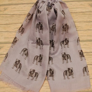 May include: A lavender scarf with a repeating pattern of brown bulldog illustrations.