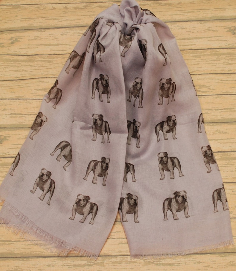 May include: A lavender scarf with a repeating pattern of brown bulldog illustrations.