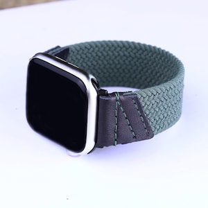 May include: A green and black braided watch band with a silver watch face. The band is made of a woven fabric with a leather accent.