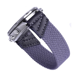 Pode incluir: Uma pulseira de relógio trançada cinza com detalhes em couro preto e a palavra "SUDDENLY" gravada na pulseira.