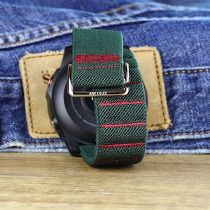 May include: A green and red striped watch band with the word "SDVLINE" printed on the buckle. The band is made of a soft, woven material.