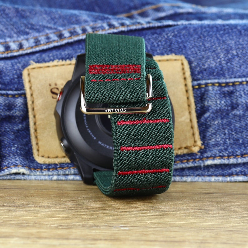 May include: A green and red striped watch band with the word "SDVLINE" printed on the buckle. The band is made of a soft, woven material.