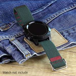 May include: A green and red watch band with a black watch face. The band is made of a soft, stretchy material and has a buckle closure. The watch is not included.
