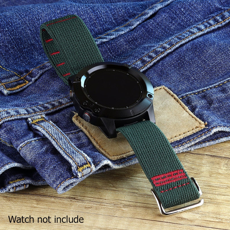 May include: A green and red watch band with a black watch face. The band is made of a soft, stretchy material and has a buckle closure. The watch is not included.