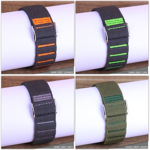 May include: Four different colored watch bands with contrasting colored stripes. The bands are made of a stretchy material and have a silver buckle. The colors are dark grey with orange stripes, dark grey with lime green stripes, dark grey with grey stripes, and khaki with army green stripes.