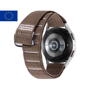 May include: A silver Samsung Galaxy Watch 4 with a brown and white striped elastic band. The watch face is black with a silver ring around it. The text on the back of the watch reads "SM-R905F-40mm Sapphire Crystal LTE GPS SATM Made in by Samsung-ME-000000000000000".