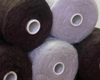 May include: A collection of five large spools of fuzzy yarn arranged in a cluster. The spools feature a soft, textured appearance in alternating shades of deep dark brown and a light, muted grey, each centered with a white plastic core.