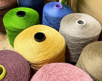 May include: A collection of large cylindrical spools of thread in various colors including lime green, bright yellow, navy blue, light blue, beige, brown, dark purple, and pink, each featuring a central plastic core for winding.