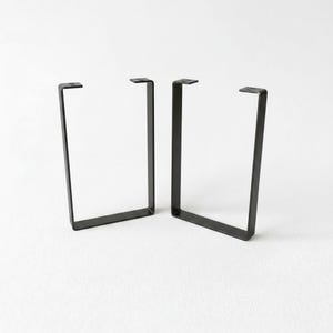 two black metal brackets with a simple, minimalist design.